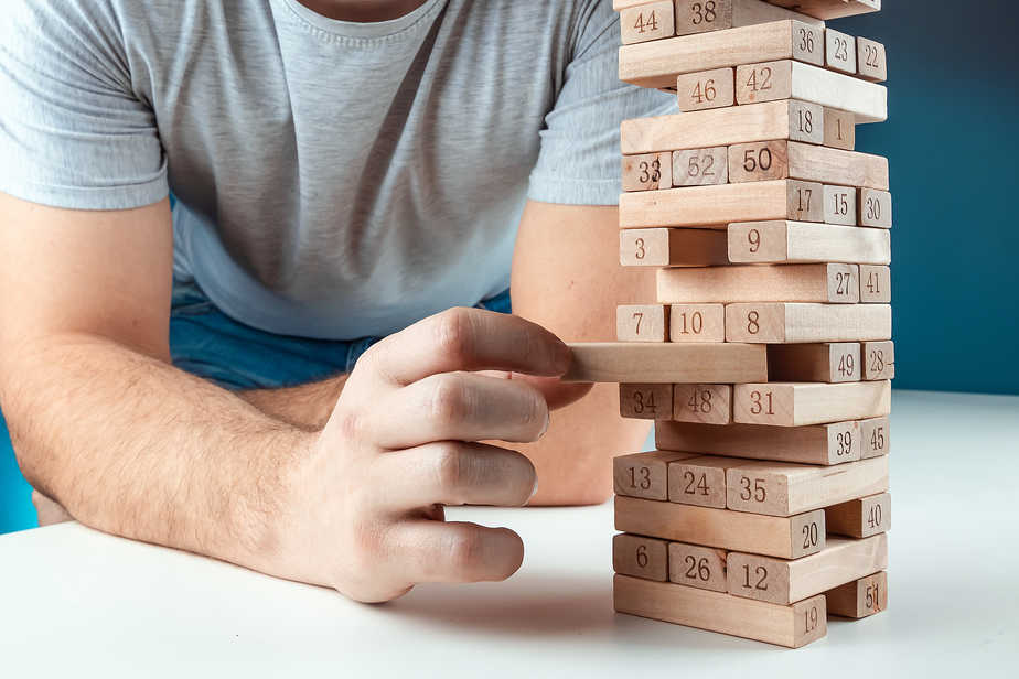 The man points to the Column of the game of jenga. The concept of a mortgage, investment risks, economic crisis, economic instability.